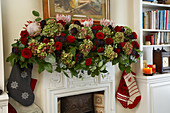 Opulent garland of roses, hydrangeas and protea flowers as Christmas decoration on traditional English mantelpiece