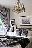 Weisses Landhaus-Schlafzimmer mit grauen Accessoires und goldfarbenem Kronleuchter