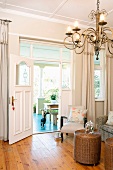 Chandelier in a traditional salon and view through an open door in the veranda
