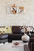 Metal wall sculpture above a dark leather sofa