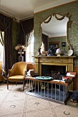 Grand room with open fireplace and half-height fender seat next to antique chair with yellow fabric upholstery