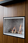 Gas fire with marble cladding and pebbles integrated into wooden wardrobe doors