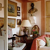 Richly decorated corner of French-style living room with bust and impressionist paintings