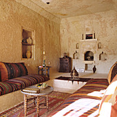 Moroccan interior with striped cushions on masonry platforms and side table of carved wood