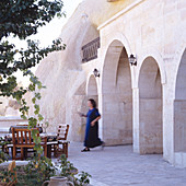 Woman walking to terrace seating area of Oriental house with arcades