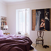 Schlichtes Schlafzimmer mit antikem Stuhl vor modernem Bild an Wand