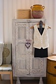 White-washed, vintage wardrobe with carved ornamentation in bedroom