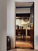 Blick vom Vorraum durch offene Tür in mediterrane Küche auf Küchentisch und antiken Wandfliesen
