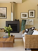 Sofa aus Rattan und rustikaler Couchtisch vor Kamin in modernem Wohnraum