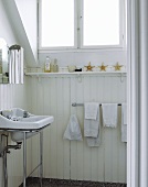 Simple bathroom with washstand in front of wooden wall painted white