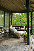Gemütliches Plätzchen auf Veranda - Fell auf Liegestuhl vor Sommerhaus mit Garten
