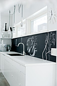 White designer kitchen with black splashback behind sink worksurface
