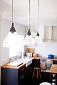 Vintage glass pendant lamps above dining table in open-plan kitchen
