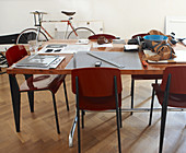 Work utensils on table and Bauhaus-style chairs in front of bicycle leaning on wall