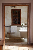 View from anteroom of cabinet with glass and lattice door built into niche in rustic bathroom