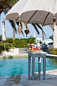 Sunny day beside the pool with refreshing fruit platter on stool