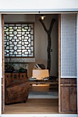 View of leather armchair and wooden window lattice in living room through open terrace door