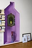 Mirror with ornate frame on wall and glass floor vase in purple-painted niche