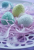 Pastel coloured Easter eggs lying on pink ribbons
