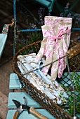 Pristine gardening gloves with feminine French patterns in old wire basket on garden chair