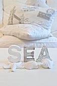 White-painted letters and seashells on white background