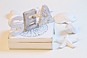 White-painted wooden letters on box surrounding by seashells