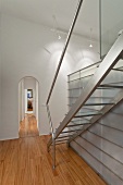 Stainless steel staircase next to glass and steel installation in interior with arched doorway and traditional ambiance