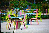 Café mit Gartenplätzen - Farbige Gartenstühle mit Tisch auf Kiesboden