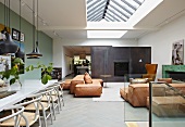 Modern interior with classic chairs in dining area and comfortable floor cushions in lounge area below skylight