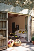 Blick durch die offene Terrassentür eines mediterranen Hauses in das Wohnzimmer