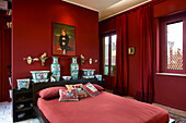 Red bedroom - double bed in front of Chinese vases on cabinet against red partition and floor-length red curtains