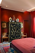 Schlafzimmer in Rot - Modernes Doppelbett vor schwarz goldenem Schrank in asiatischem Stil vor roter Wand