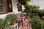 Wooden garden bench and pots of herbs and flowering plants on farmhouse veranda
