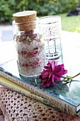 Scatter cushion with crocheted cover, books, rose bath salts, drinking glass and rose