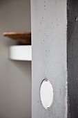 Round, white light switch in exposed concrete pillar