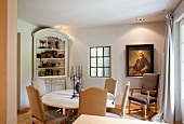 Elegant, country-house-style dining area with antique armchair below historical portrait on wall