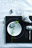 Place setting for summer party: decorative fennel and labelled pebbles, candle and salt on pebbles, outlines of cutlery and plate