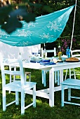 Cloth painted with stencilled pattern as awning above set table in garden