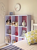 Child's bedroom - soft toys and vases on lilac shelving next to bed and below clock on wall painted pale grey