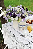 Gedeckter Frühstückstisch mit Blumenstrauss im Garten