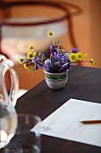 Schreibtisch mit Briefpapier, im Hintergrund kleine Vase mit Gartenblumen