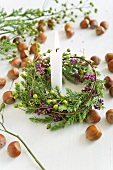 Hazel nuts and candle with wreath of callicarpa and conifer twigs