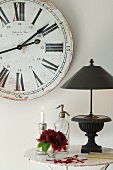 Black table lamp with Ancient Greek style base in front of vintage wall clock