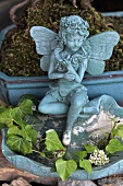 Fairy figurine on edge of stone dish decorated with leaves