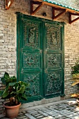 Green-painted, carved front door and small porch on brick facade