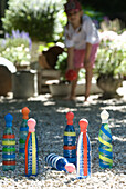 Child plays skittles with colourful bottles in the gravel garden