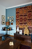 Antique collectors' items and large, decorative kilim on pale blue living room wall