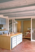Modern, open-plan kitchen with Mediterranean ribbed ceiling and terracotta floor; sleeping area separated by translucent sliding doors in background