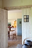 Zimmer mit offener Tür und Blick in die schlichte Küche mit gemustertem Fliesenboden