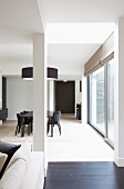 Blick in offenen Designer Wohnraum mit Essplatz in Schwarz unter Designer Hängelampe vor raumhohen Terrassenfenstern
